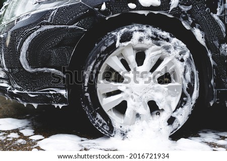 car wash with active foam soap. cleaning wheel tire. commercial cleaning service concept.