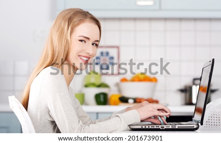 Beautiful caucasian woman working on laptop. Kitchen background.