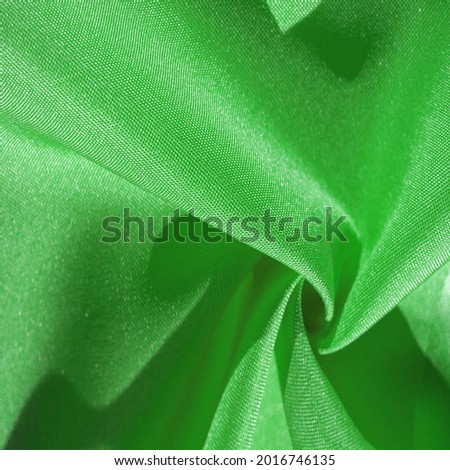 Silk fabric, green forest. Pleats in silky green fabric, close-up, full frame. Texture background pattern