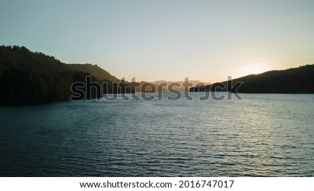 Bird's-eye view of the sunrise over the river with hilly terrain.