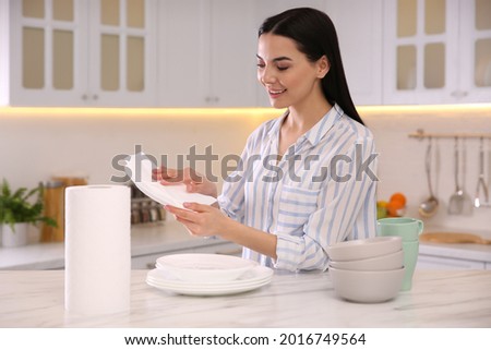 Woman wiping plate with paper towel in kitchen Royalty-Free Stock Photo #2016749564