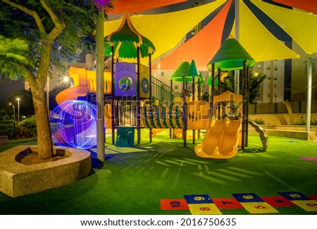 Children's playground in a residential area surrounded by green trees in the evening. Spherical ball drawing with light. Long exposure Israel Ashkelon July 2021