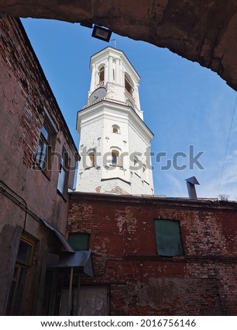 View from the arch to the Old Clock Tower, a former bell tower, in the city of Vyborg against the blue sky.