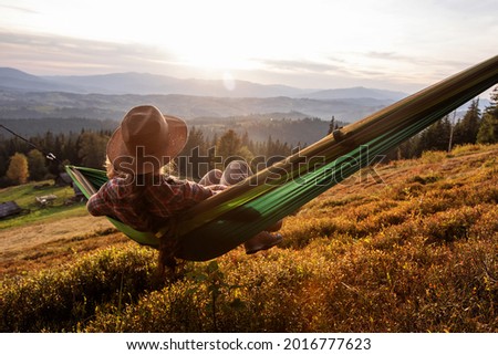 tired woman resting after climbing in a hammock at sunset Royalty-Free Stock Photo #2016777623