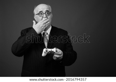 Studio shot of overweight senior businessman wearing eyeglasses against brown background