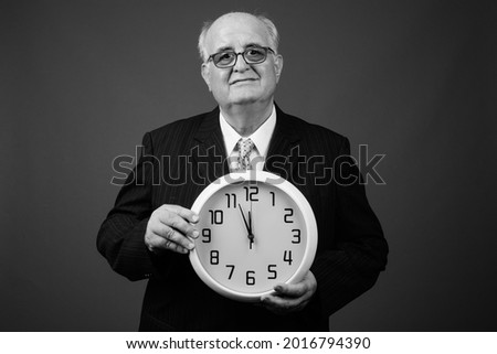 Studio shot of overweight senior businessman wearing eyeglasses against background