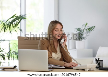 Secretary talking on phone at wooden table in office Royalty-Free Stock Photo #2016796547