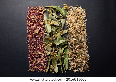 Top view picture of dried herbs arranged in the line, isolated on black.
