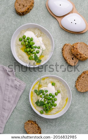 Vegetable cream soup with green peas and sprouts on a cement background. Selective focus.