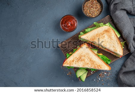 Two club sandwiches with ham and vegetables on a gray-blue background. Top view, copy space. Royalty-Free Stock Photo #2016858524