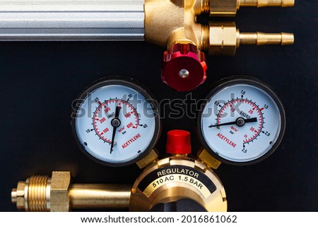 Reducer for a gas cylinder with acetylene and part of a gas burner on a black background, close-up. Royalty-Free Stock Photo #2016861062
