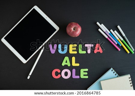 School materials with the phrase BACK TO SCHOOL, in Spanish on a black background. Copy space.