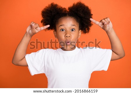 Photo of little impressed girl point hair wear white t-shirt isolated on orange color background