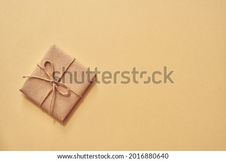 Christmas present wrapped in ecological recycled paper on pastel background with copy space - zero-waste concept