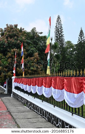 Indonesian red and white flags and banners on fences, yards and sidewalks ahead of independence day.