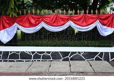 Indonesian red and white flags and banners on fences, yards and sidewalks ahead of independence day.