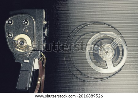 Old amateur movie camera and reel of film stock on black background