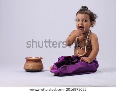 Adorable Indian kid dressed up as little krishna  Shrikrishna or kanha kanhaiya on fancy dress Gokulashtami festival. eating curd butter