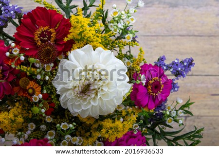 Zinnia flowers and other flowers in a beautiful bouquet on old grunge wooden background (Erígeron)