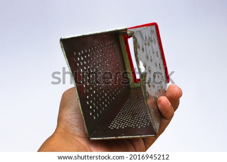 Grater on hand with red handle isolated on white background. Kitchen utensil background stock images.