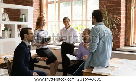 Happy inspired young mixed race colleagues discussing business ideas at brainstorming meeting in modern loft office. Friendly sincere motivated millennial multiracial employees developing project. Royalty-Free Stock Photo #2016949895