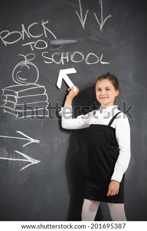 Back to school . Cute little girl standing by a black school board 