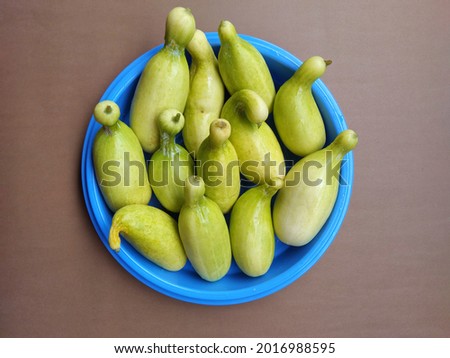 Cucumber in a blue container and a brown background.