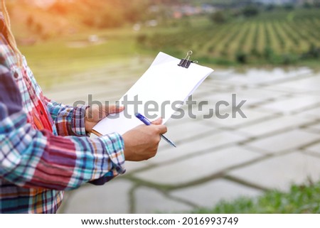 Farmer stands on the field and keeps a record of planning work for the day.