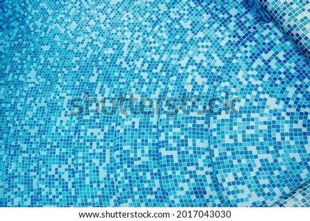 blue ceramic mosaic at the bottom of the swimming pool. Bathing area in the background. Tiles in blue tones in the pool. Concept wallpaper background space. Place for text. High quality photo