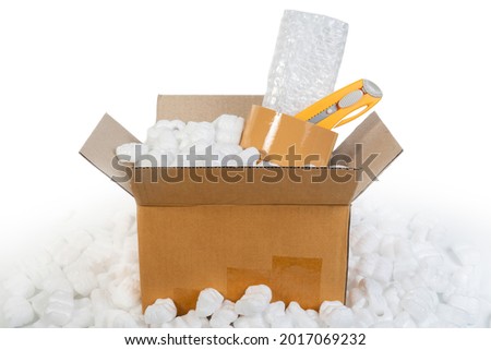Packing accessories polystyrene plastic foam, parcel tape, cutter, plastic bubble shockproof wrap in parcel paper box for packing and shipping. Packing cardboard box and accessories concept. Royalty-Free Stock Photo #2017069232