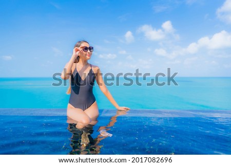 Portrait beautiful young asian woman relax smile leisure around outdoor swimming pool in resort hotel with sea ocean view