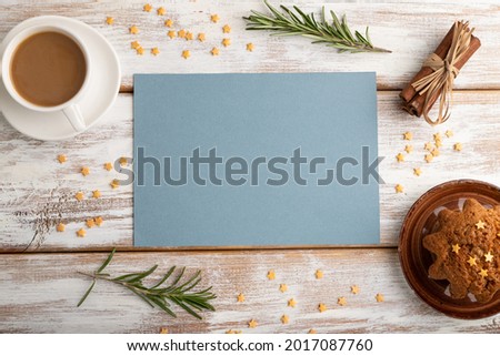 Blue paper sheet mockup with cup of coffee and cake on white wooden background. Blank, top view, flat lay, still life.
