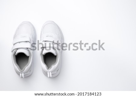 flat lay two white girl sneakers with velcro fasteners isolated on a white background.