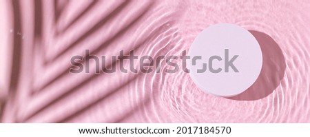 Pink transparent clear calm water surface. Texture with palm tree shadows with pink podium. Trendy abstract summer nature background for product presentation. Flat lay cosmetic mockup. Panoramic