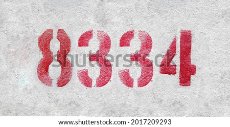 Red Number 8334 on the white wall. Spray paint. Number eight thousand three hundred and thirty four.