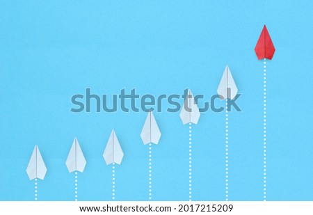 Leadership concept with red paper plane leading among white on blue background with copy space