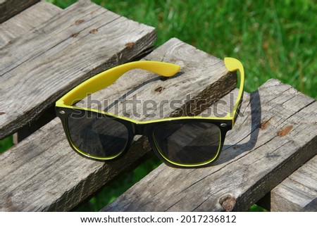Black sunglasses for women with a yellow frame on a wooden board
