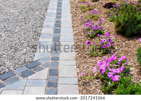 Hardscape detail from an elegant luxury landscaping installation using cobblestones and precast flagstone look pavers. Royalty-Free Stock Photo #2017241066