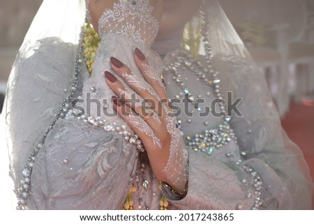 beautiful henna design in the hands of the bride. mehendi artist painting henna on hand. A Javanese, Indonesian bride displays a henna design on her hand.