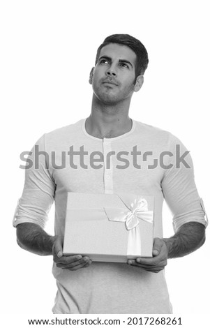 Studio shot of young handsome Iranian man with beard stubble isolated against white background in black and white