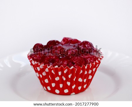 Delicious juicy raspberry tartlet with raspberries and jelly topping stock images. Creamy red raspberry cupcake on a white background stock photo. Raspberry gelatin dessert frame images