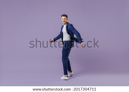 Full size young successful employee business man lawyer 20s wear formal blue suit white t-shirt work in office move stroll fooling around have fun isolated on pastel purple background studio portrait