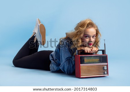 Disco, party time. Portrait of attractive woman in retro 90s fashion style, outfit isolated over blue studio background. Concept of eras comparison, beauty, fashion and youth. Royalty-Free Stock Photo #2017314803