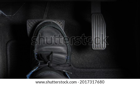 Man foot and accelerator and brake pedal inside the car or vehicle and copy space which black color leather shoe stepped on it for speed up or control automobile pace power. Automobile Driving concept Royalty-Free Stock Photo #2017317680