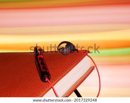 Musical headphone kept upon note book with light effect on background.