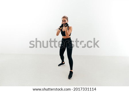 Shot of a female boxer holding a stance. Woman in gloves exercising indoors. Royalty-Free Stock Photo #2017331114