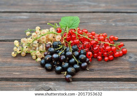 Ripe berries of black, red and white currants on a wooden table. Three varieties of currants belong to the Ribes genus of the gooseberry family. Royalty-Free Stock Photo #2017353632