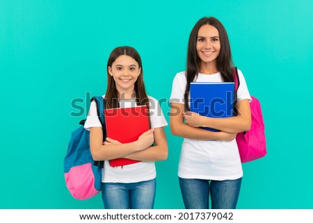 happy daughter pupil and mother or teacher hold school workbook for studying, back to school