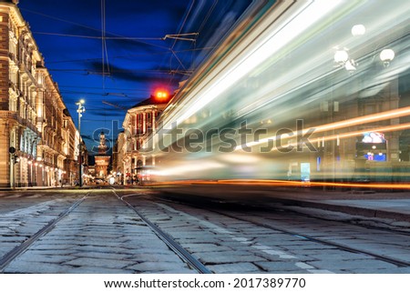 Tram in motion blur passing on a shopping street in the center of Milan in Italy
