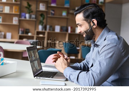 Latin indian smiling businessman wearing headset having virtual team meeting group call chatting with diverse people in customer support. Video conference call on computer with manager and employees. Royalty-Free Stock Photo #2017392995